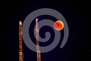 Construction crane on the background of a full red moon. Red moon, total lunar eclipse.