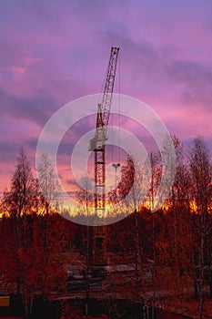 Construction crane on the background of the twilight sky at the construction site in autumn