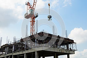 Construction crane brings a tank of concrete to the construction structure