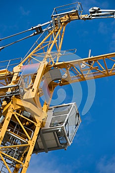 The construction crane and the building against the blue sky