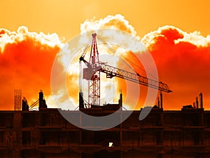 Construction crane building house during dramatic sunset backdrop