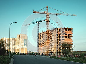 Construction crane building multystory residential building at evening time