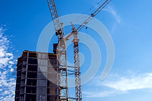 Construction crane on a building site against blue sky background. Development concept