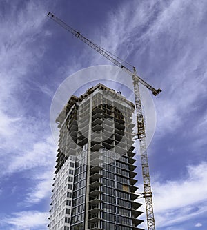 A construction crane builds a tall downtown apartment building