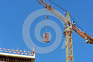 Construction crane with cargo on the background blue sky