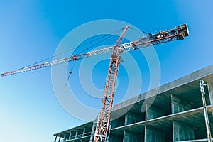 Construction crane at a construction site in the city against the blue sky. Construction of a new building. The concept of