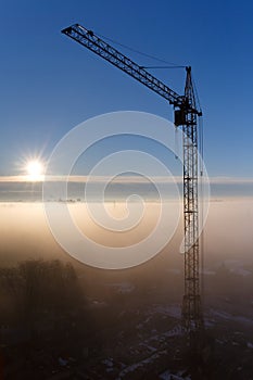 Construction crane in the fog at dawn