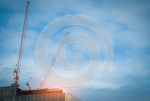 Construction crane on high-rise building with blue sky and white clouds. Construction site of commercial building or condominium