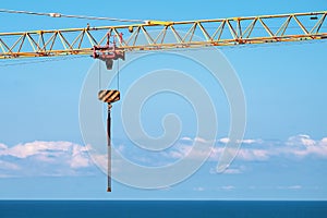 Construction crane and hook with chain on blue sky background