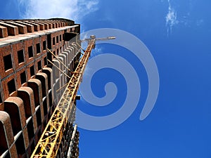 Construction crane near building on blue sky background.