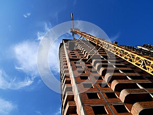 Construction crane near building on blue sky background.