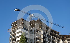 A construction crane near a high rise building under construction.