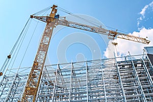 Construction crane with a new steel structure building. Against the background of a blue sky with clouds