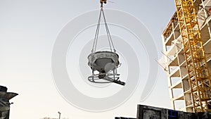 Construction crane over a building under construction. The crane lifts the container with liquid concrete. A tower crane