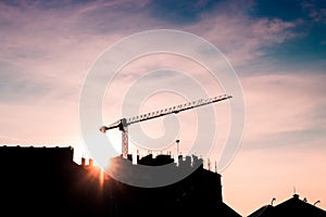 Construction crane on site with silhouette of building and workers