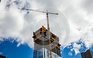 Construction crane on a skyscraper building, blue sky background, spring day