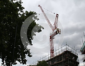 Construction crane towers on cloudy sky with some background