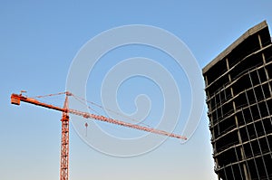 Construction cranes and building silhouettes over sun at sunrise. Abstract Industrial background of blue sky and