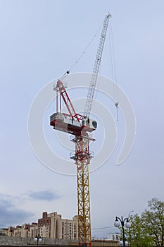 Construction cranes and buildings on background cloudy sky