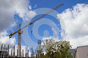 Construction cranes and buildings on background cloudy sky