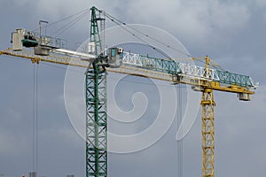 Construction cranes and high-rise building under construction against blue sky.