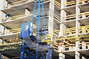 Construction cranes and high-rise building under construction against blue sky.