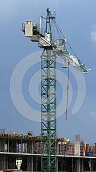 Construction cranes and high-rise building under construction against blue sky.