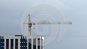 Construction cranes and high-rise building under construction against blue sky.