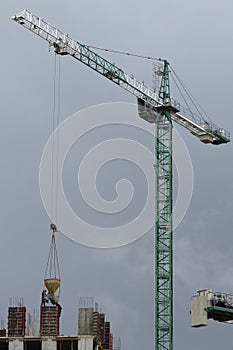 Construction cranes and high-rise building under construction against blue sky.