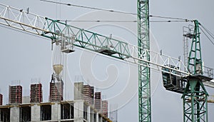 Construction cranes and high-rise building under construction against blue sky.