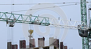 Construction cranes and high-rise building under construction against blue sky.