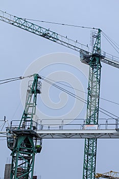 Construction cranes and high-rise building under construction against blue sky.