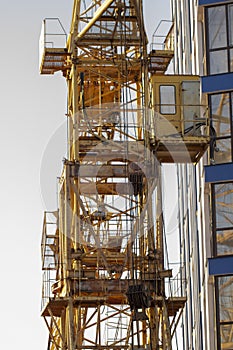 Construction cranes and high-rise building under construction against blue sky.