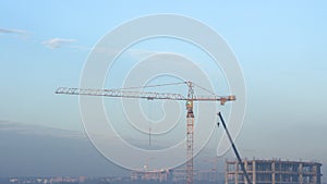 Construction cranes and high-rise building under construction against blue sky.