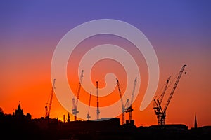 Construction cranes silhouettes on a Cityscape sunset sky background