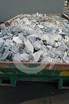 Construction debris in a big container. Pieces of mortar and wood splitter fill the whole volume.