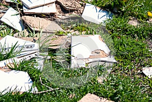 Construction debris is dumped in the grass by the side of the road. Discarded ceramic tiles. Pollution of nature.