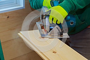 Construction details male worker of carpenter using circular saw for cutting wooden boards