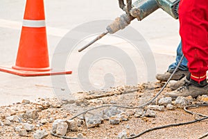 Construction drilling repair worker on road surface with heavy duty machine drill motion