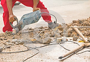 Construction drilling repair worker on road surface with heavy duty machine drill motion