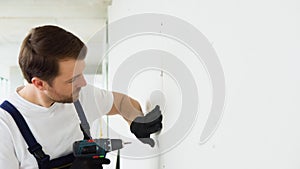 Construction drywall worker installing plasterboard sheet to wall. Drywall worker works on building site in a house