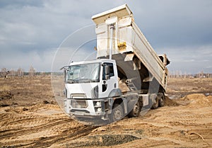 Construction dump truck performs earthwork at a construction site