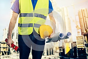 construction engineer with blueprint rolls at building site