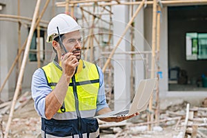 Construction engineer builder work in construction site. Architect home project foreman chief designer radio call with laptop