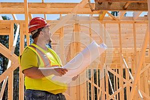 Construction engineer checking quality works of wooden frame using architecture blueprint plan during construction work