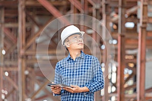 Construction engineer man checking project at the building site, Foreman worker in hardhat at the infrastructure construction site