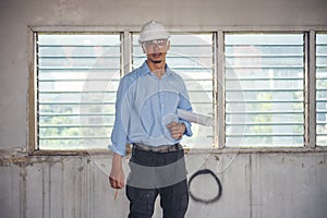 Construction engineer man hold blueprint wear blue shirt safety white hard hat at construction site industry labor worker.