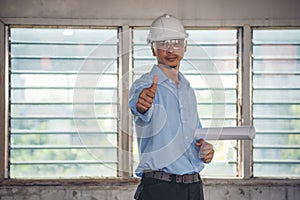 Construction engineer man hold blueprint wear blue shirt safety white hard hat at construction site industry labor worker.