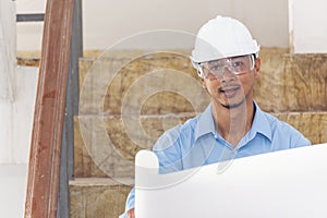 Construction engineer man hold blueprint wear blue shirt safety white hard hat at construction site industry labor worker.