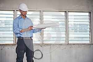 Construction engineer man hold blueprint wear blue shirt safety white hard hat at construction site industry labor worker.